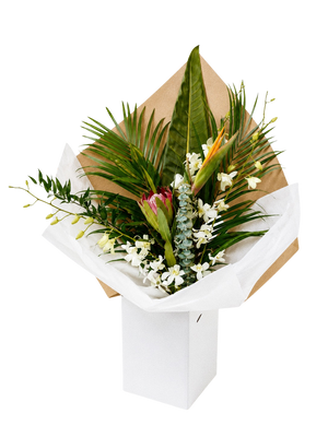 Bouquet of tropical greenery and white tropical flowers wrapped in brown paper and white tissue paper on a white background in Vancouver BC